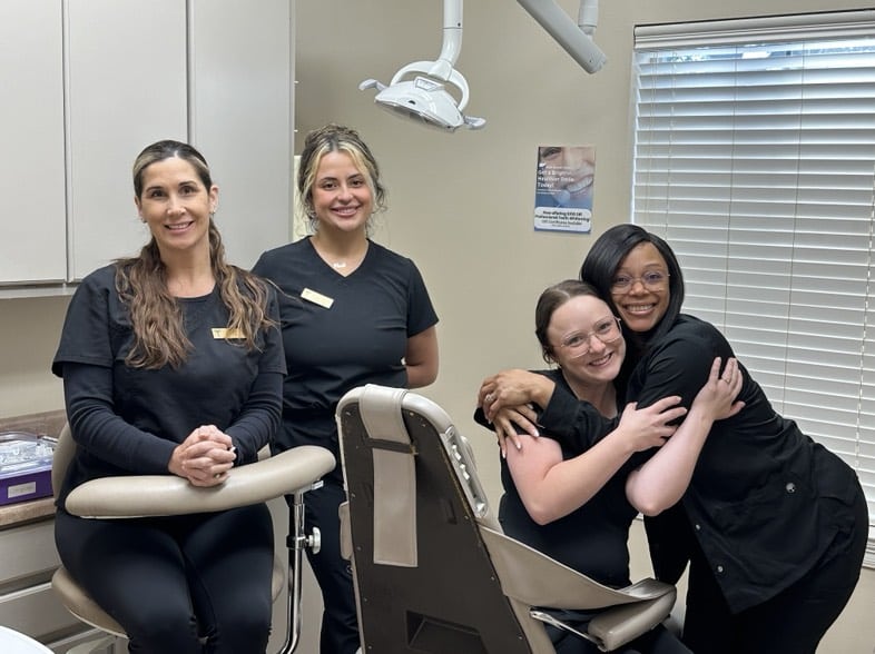 Four women smiling in a dental office.